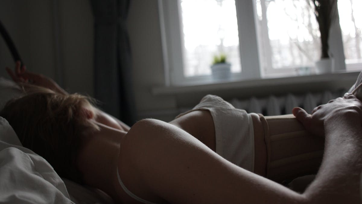 A serene scene of a woman resting in bed bathed in soft morning light.